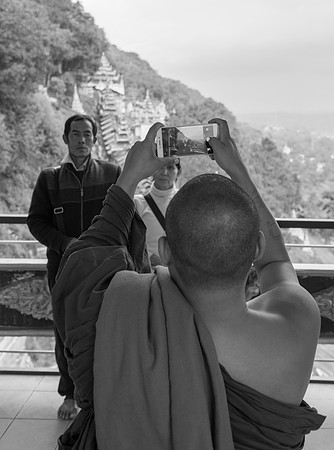 Monk photographing tourists bw